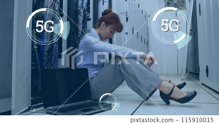 Digital composite of a Caucasian woman sitting beside a laptop in a corridor of server towers while Digital composite of a Caucasian woman sitting beside a laptop in a corridor of server towers while 115910015