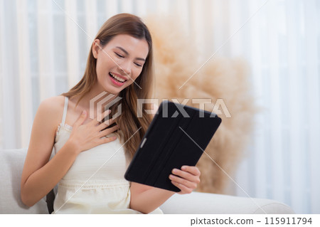 Young asian woman sitting on sofa using digital tablet computer for video call. Young asian woman sitting on sofa using digital tablet computer for video call. 115911794