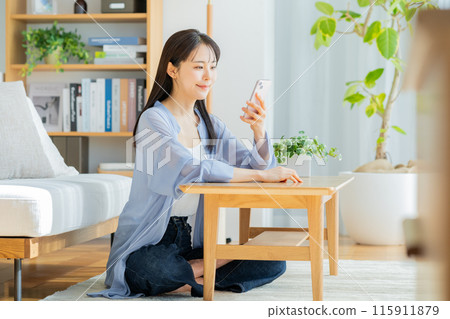 一位女士在客廳放鬆時看著智慧型手機 115911879