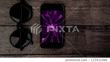 Image of smartphone with purple light trails on screen and sunglasses on desk 115912066