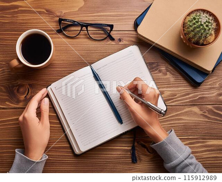 Hands taking notes on a wooden desk 115912989