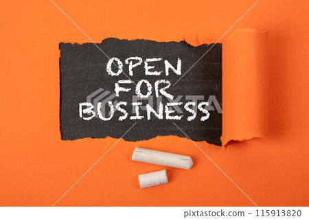Open for business. Text under torn orange paper on a blackboard 115913820