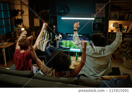 Rear view of four young male friends enjoying watching soccer match on TV late in evening Rear view of four young male friends enjoying watching soccer match on TV late in evening 115915091