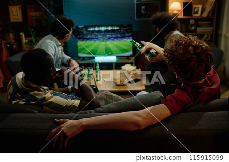 Rear view of four young male friends spending evening indoors watching soccer match on TV and drinking beer Rear view of four young male friends spending evening indoors watching soccer match on TV and drinking beer 115915099