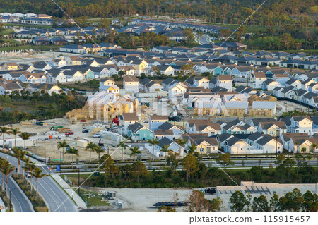 Unfinished frames of inexpensive homes with wooden roof beams under construction. Development of residential housing in US suburbs. Real estate market in the USA Unfinished frames of inexpensive homes with wooden roof beams under construction. Development of residential housing in US suburbs. Real estate market in the USA 115915457