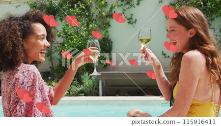 Multiple red hearts floating against two diverse female friends toasting drinks by the pool 115916411