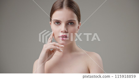 Beauty, health, cosmetics, anti-aging therapy and skin care concept - young beautiful brunette Caucasian woman posing and looking at the camera with a calm confident look like in a mirror 115918859