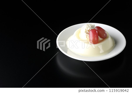 Panna cotta with cream and grapes photographed against a black background 115919042