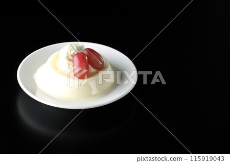 Panna cotta with cream and grapes photographed against a black background Panna cotta with cream and grapes photographed against a black background 115919043