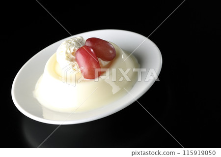 Panna cotta with cream and grapes photographed against a black background Panna cotta with cream and grapes photographed against a black background 115919050