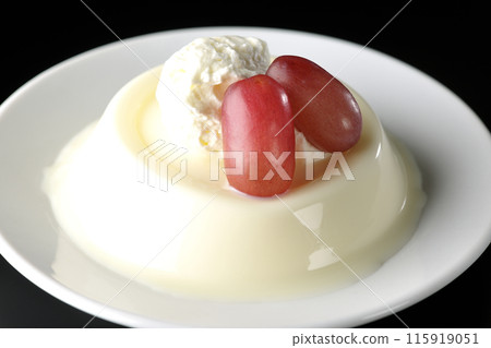 Panna cotta with cream and grapes photographed against a black background 115919051