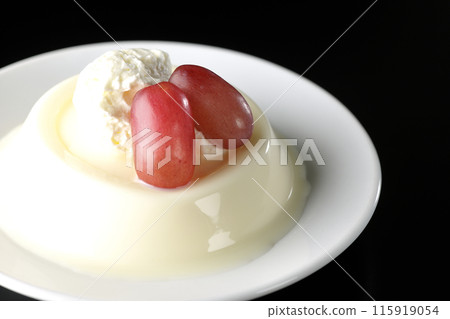 Panna cotta with cream and grapes photographed against a black background 115919054