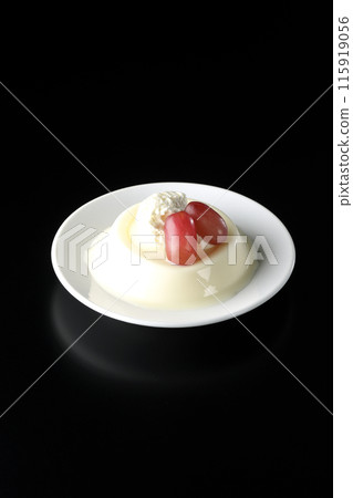 Panna cotta with cream and grapes photographed against a black background 115919056
