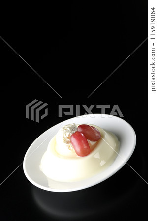 Panna cotta with cream and grapes photographed against a black background Panna cotta with cream and grapes photographed against a black background 115919064