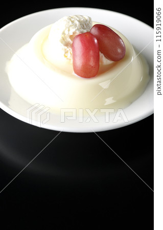 Panna cotta with cream and grapes photographed against a black background 115919066