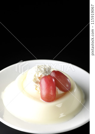 Panna cotta with cream and grapes photographed against a black background 115919067