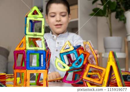 A child plays with a magnetic construction set. Interesting educational toys. A child plays with a magnetic construction set. Interesting educational toys. 115919077