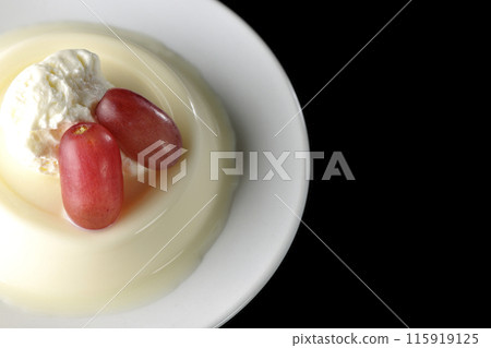 Panna cotta with cream and grapes, shot from above on a black background Panna cotta with cream and grapes, shot from above on a black background 115919125