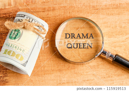 Text DRAMA QUEEN through a magnifying glass with American dollars lying next to it 115919513