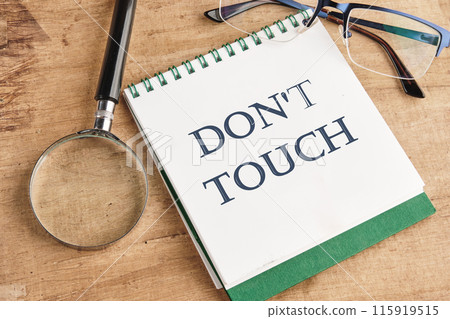Words DO NOT TOUCH written on a notebook in a composition with a magnifying glass, glasses and a pencil Words DO NOT TOUCH written on a notebook in a composition with a magnifying glass, glasses and a pencil 115919515