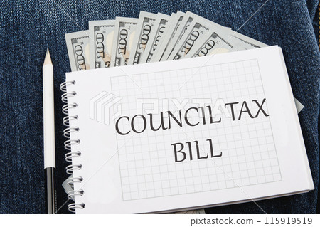 COUNCIL TAX BILL word on a checkered notebook in a composition with dollars bills and a pencil 115919519
