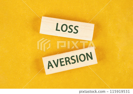 LOSS AVERSION text written on wooden blocks on a bright yellow mustard background LOSS AVERSION text written on wooden blocks on a bright yellow mustard background 115919531