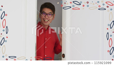 Image of colourful patterned frame over smiling asian man in glasses welcoming at front door 115921099