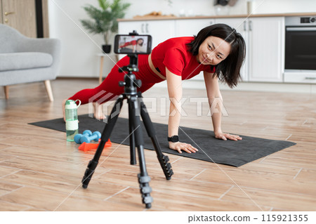 Woman doing push-ups during online workout at home Woman doing push-ups during online workout at home 115921355