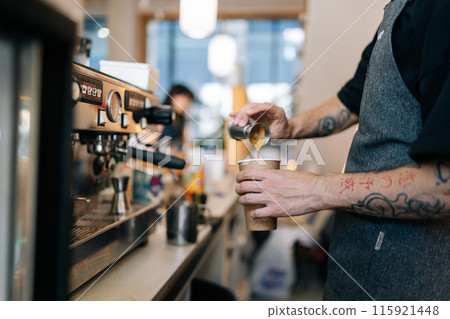 Cropped shot of unrecognizable barista male preparing tasty coffee drink for customer in small business, holding metal pot pouring coffee in espresso shot. Beverage drink for breakfast in cafe. Cropped shot of unrecognizable barista male preparing tasty coffee drink for customer in small business, holding metal pot pouring coffee in espresso shot. Beverage drink for breakfast in cafe. 115921448