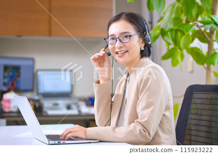 一位戴著耳機在辦公室工作的中年婦女 115923222