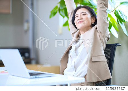 Middle-aged woman stretching in the office 115923387