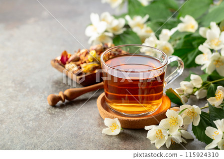Cup of jasmine tea and fresh jasmine flowers on a stone table. 115924310