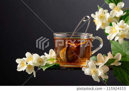 Cup of jasmine tea and fresh jasmine flowers on a black background. 115924315