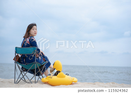 woman relax and sit on beach chair with her cat sit on duck rubber ring on sand beach 115924362