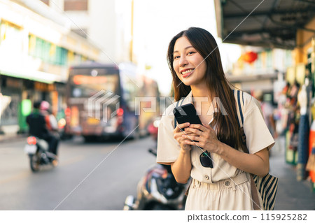 Smiling Asian woman traveller backpacker using application of taxi service app on smart phone 115925282