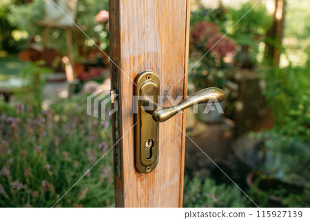 Close up of antique wooden front door handles, doors opening to a beautiful greenhouse or conservatory. Interior of a garden greenhouse. 115927139