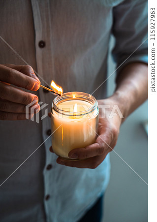 Man holding a burning candle in his hands, elegant young man with candle jar, meditation and mindfulness concept 115927963