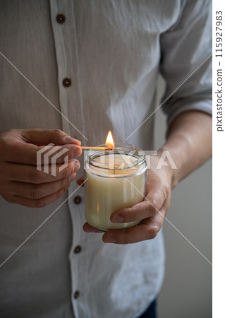 Man holding a burning candle in his hands, elegant young man with candle jar, meditation and mindfulness concept Man holding a burning candle in his hands, elegant young man with candle jar, meditation and mindfulness concept 115927983