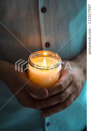 Man holding a burning candle in his hands, elegant young man with candle jar, meditation and mindfulness concept Man holding a burning candle in his hands, elegant young man with candle jar, meditation and mindfulness concept 115927997
