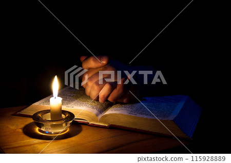 Hands folded in prayer over Scriptures 115928889
