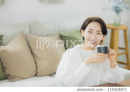 Middle-aged woman drinking coffee in the living room 115928971