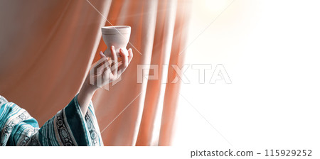 A hand in ancient clothing holds a clay bowl A hand in ancient clothing holds a clay bowl 115929252