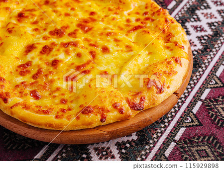 Delicious cheese pizza on traditional tablecloth Delicious cheese pizza on traditional tablecloth 115929898