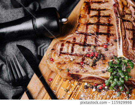 A big grilled steak on a wooden plate 115929998