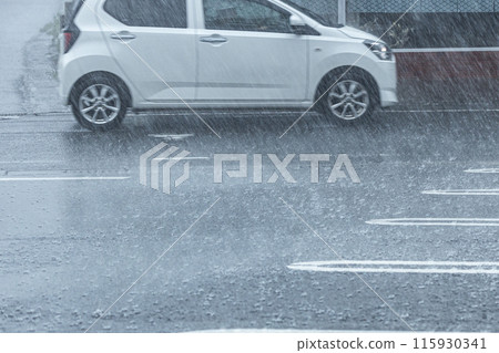 下雨天，一輛白色汽車在路上行駛 115930341