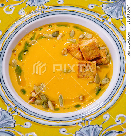 Vibrant pumpkin soup with croutons in decorative bowl Vibrant pumpkin soup with croutons in decorative bowl 115930364
