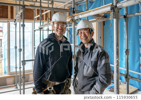 Portrait of two middle-aged men wearing work clothes standing at a construction site 115930655