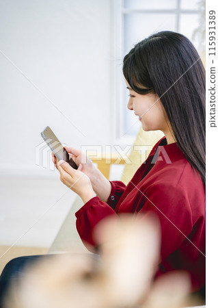 一個女人在客廳裡看著她的智能手機 一個女人在客廳裡看著她的智能手機 115931389