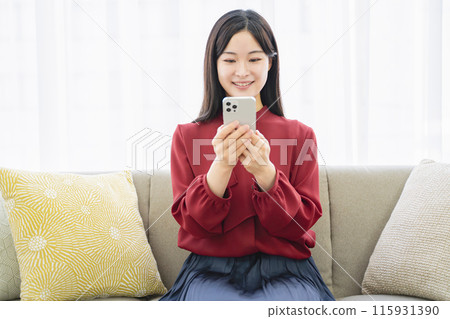 一個女人在客廳裡看著她的智能手機 115931390