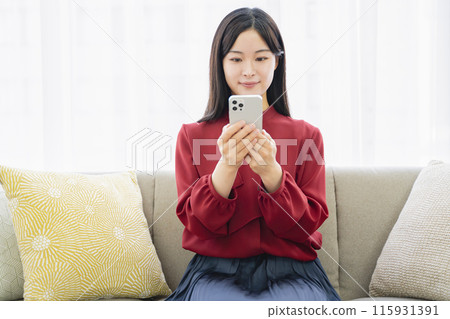 A woman looking at her smartphone in the living room 115931391